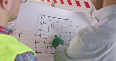 Becerikli ustabaşı ve iş arkadaşı yenileme sırasında kat planı üzerinde çalışıyorlar. Yerleşim yerindeki mühendisler çözümlere danışmanlık yapma konusunda konuşuyorlar.