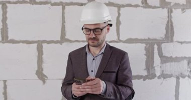 Mühendis, akıllı telefondan bilgi almaktan sıkılmış. Ceket uzmanı, duvarın karşısında duran daireyi yenileme sorununu çözmek için modern teknolojiler kullanıyor.