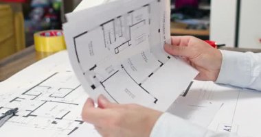 Erkek ofis çalışanı, yer açmak için düz plandaki sürgülü kapıları kullanıyor. Mimar, yaz aylarında çapraz havalandırma için pencerelerin yerleştirilmesini tartışır