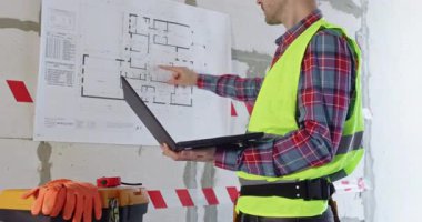 Profosyonel çizim bilgilerinin analizini bitiriyor. İş kıyafetleri mühendisi duvardaki kat planını inceliyor ve yenileme işlemini başlatmaya hazırlanıyor