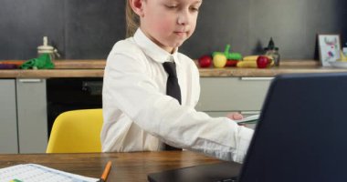 Liseli çocuk not defterine not alır ve kağıtları incelerken dizüstü bilgisayarına yazar. Çocuk eylemleri, mutfakta öğrenim ile ilgili belgelerin çoklu görevlendirilmesi ve düzenlenmesini öneriyor