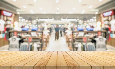 Boş ahşap masa üstü ve bulanık kıyafet butiği iç alışveriş merkezinin arka planı.