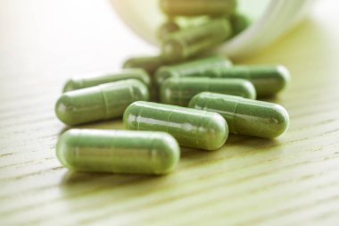 Ahşap masasında şişe bulunan bitkisel ilaç kapsülleri.