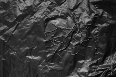 black crumpled and creased plastic poster texture background