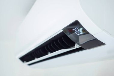 Beyaz duvar odasının arka planında klima var.