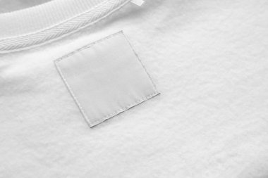 Blank white laundry care clothes label on fabric texture background