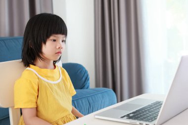 Küçük Asyalı kız öğrenci çevrimiçi evde dizüstü bilgisayar kullanıyor.