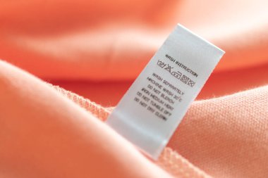 White laundry care washing instructions clothes label on pink cotton shirt
