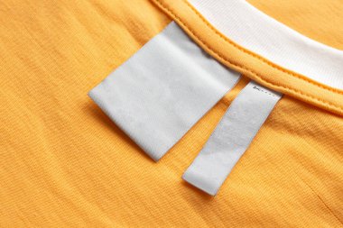 Sarı kumaş arkaplanda boş beyaz çamaşırhane kıyafetleri etiketi