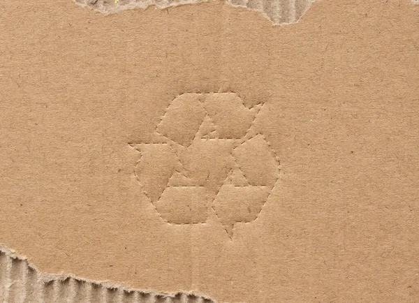 茶色の段ボール紙の背景にリサイクルシンボル — ストック写真