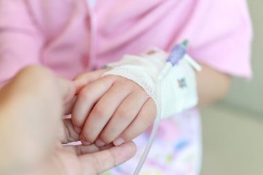Anne hastanede serum fizyolojik solüsyonuyla çocuk elini tutuyor.