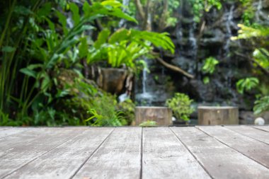 Ürün gösterimi için yeşil tropikal bahçe arka planına sahip boş ahşap masa