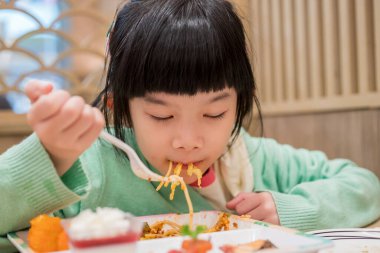 Küçük tatlı Asyalı kız yemek yiyor.