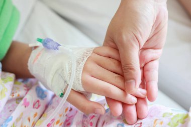Anne hastanede serum fizyolojik solüsyonuyla çocuk elini tutuyor.