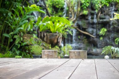 Ürün gösterimi için yeşil tropikal bahçe arka planına sahip boş ahşap masa
