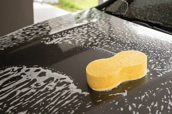 car cleaning and washing with yellow sponge and foam soap