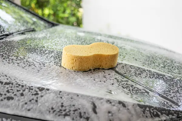 car cleaning and washing with yellow sponge and foam soap