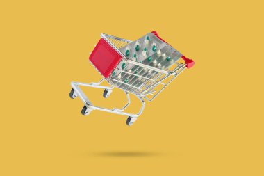 Medicine pills capsule in shopping cart isolated on yellow background clipart