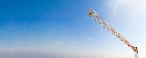 Industrial construction tower crane with blue sky background at building site