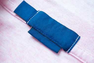 Pembe gömlek kumaş arka planında boş mavi çamaşırhane kıyafetleri etiketi