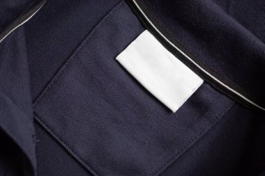 Siyah gömlek kumaş arka planında beyaz çamaşırhane kıyafetleri etiketi