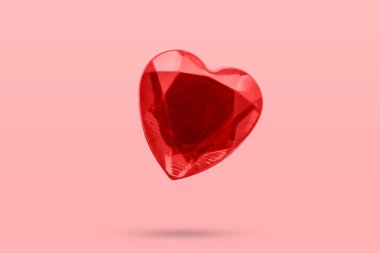 Kırmızı kalp şekli kristal sevgililer günü sembolü etiketi pembe arka planda izole edilmiş.