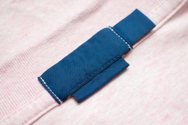 Pembe gömlek kumaş arka planında boş mavi çamaşırhane kıyafetleri etiketi