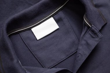 Siyah gömlek kumaş arka planında beyaz çamaşırhane kıyafetleri etiketi