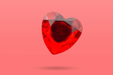 Kırmızı kalp şekli kristal sevgililer günü sembolü etiketi pembe arka planda izole edilmiş.