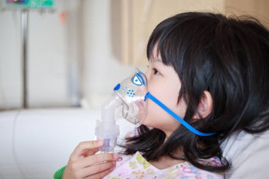 Solunum tedavisi için nebulizör solumuş küçük Asyalı kız.