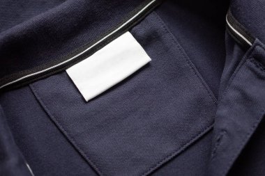 Siyah gömlek kumaş arka planında beyaz çamaşırhane kıyafetleri etiketi