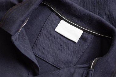 Siyah gömlek kumaş arka planında beyaz çamaşırhane kıyafetleri etiketi