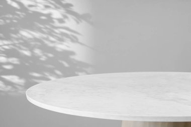 Yuvarlak mermer masa üstü ağaç yaprakları ile beyaz duvar arkaplanı üzerine gölge damla ürün görüntüleme için