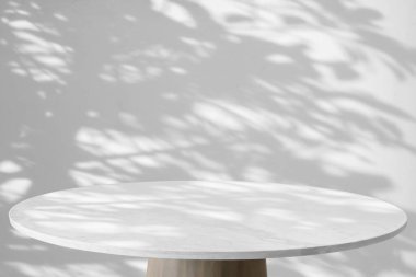 Yuvarlak mermer masa üstü ağaç yaprakları ile beyaz duvar arkaplanı üzerine gölge damla ürün görüntüleme için