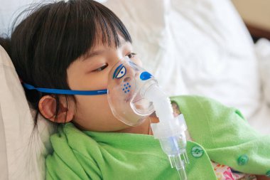 Sick little asian girl inhalation with nebulizer for respiratory treatment clipart