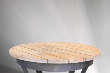 Yuvarlak ahşap masa üstü beyaz duvar zemininde soyut gölge düşüşü ile model ürün görüntüsü için