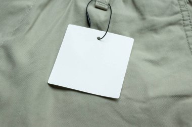 Gri kumaş doku arka planında boş beyaz kıyafet etiketi