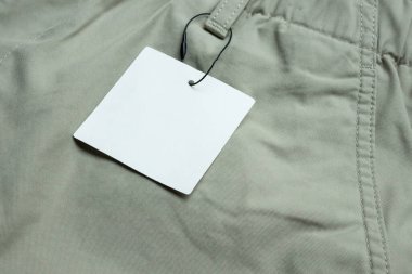 Gri kumaş doku arka planında boş beyaz kıyafet etiketi