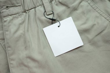Gri kumaş doku arka planında boş beyaz kıyafet etiketi