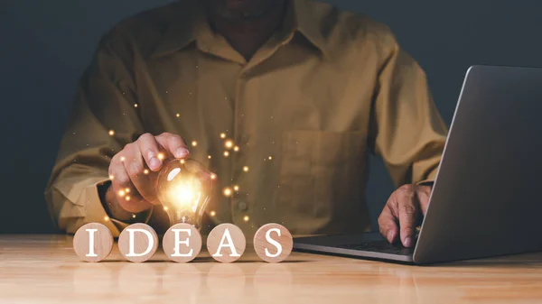 Inspiration of ideas for sustainable business development. An Idea of innovation and inspiration concept. Hand of a man holding illuminated light bulb, concept creativity with bulbs that shine glitter
