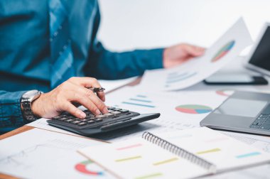 İşadamı, projenin başarısını, mali raporun doğruluğunu sağlamak için gerekli belgeler, planlama üzerinde çalışırken finansal tahminleri, pazarlama stratejilerini titizlikle hesaplıyor.