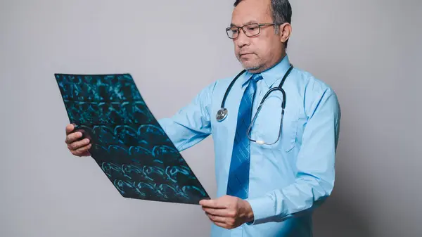 Doctor, lab concept. Professional doctor, holding and scrutinizing an X-ray film, works diligently in hospital laboratory, ensuring precise examination and accurate diagnosis in field of medicine