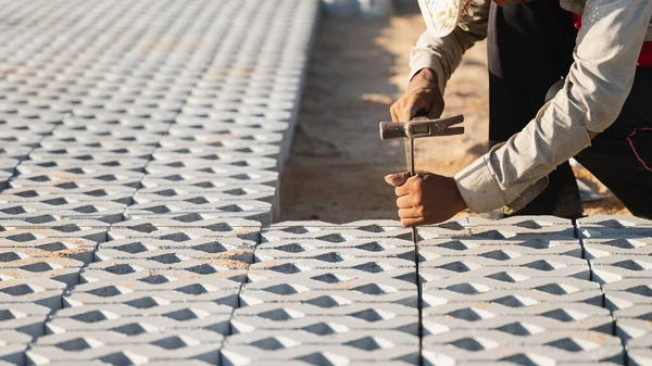Kaldırım taşları konsepti kuruluyor. Çalışkan bir adam inşaat alanında çalışıyor, inşaat alanında dayanıklı ve iyi döşenmiş bir zemin oluşturmak için kaldırım taşları ve çimento döşüyor.