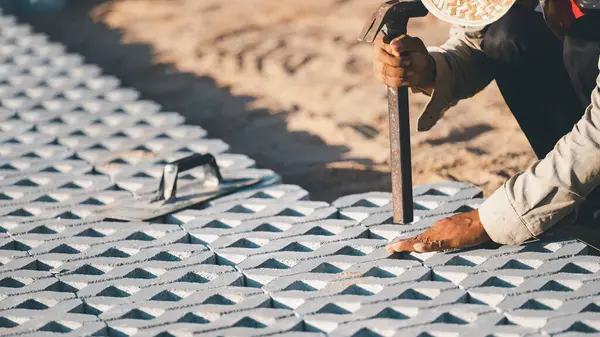 Kaldırım taşları konsepti kuruluyor. Çalışkan bir adam inşaat alanında çalışıyor, inşaat alanında dayanıklı ve iyi döşenmiş bir zemin oluşturmak için kaldırım taşları ve çimento döşüyor.