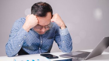 Uykulu işadamı, çalışmaktan dolayı stresli, ofisteki dizüstü bilgisayarına odaklanmak için çabalıyor, işin baskılarını yansıtıyor..