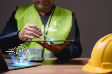 Bir mühendis yeşil yelekli bir tablet tutuyor. Tablette bir inşaat alanının resmi var. çalışma, sanayi, proje