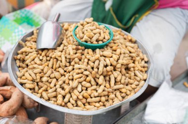 Önünde bir kase fıstık olan bir insan masada oturuyor.