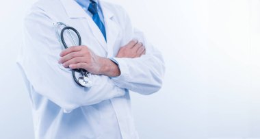 Profesyonel bir erkek doktor, kolları bağlı, steteskop tutan, tıbbi alanda uzmanlığı ve güvenilirliği sembolize eden, güvenilir bir şekilde ayakta duruyor.