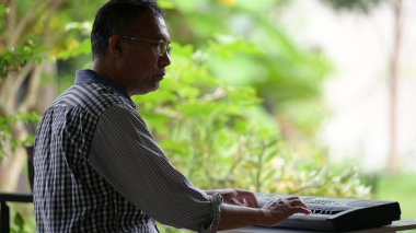 Dizüstü bilgisayarla çalışan Asyalı kıdemli adam.