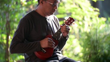 Son sınıf öğrencisi bahçede ukulele çalıyor.